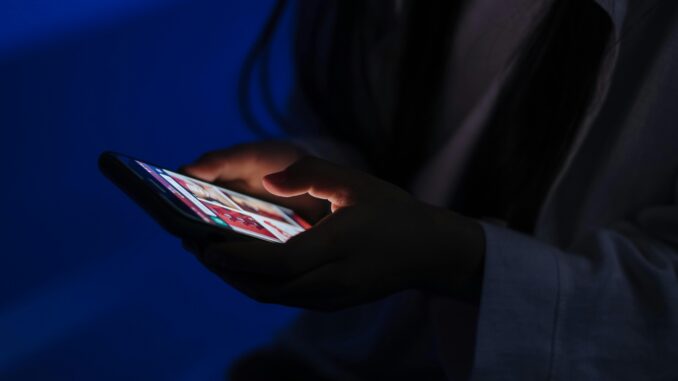 A person using a smartphone in a dark setting
