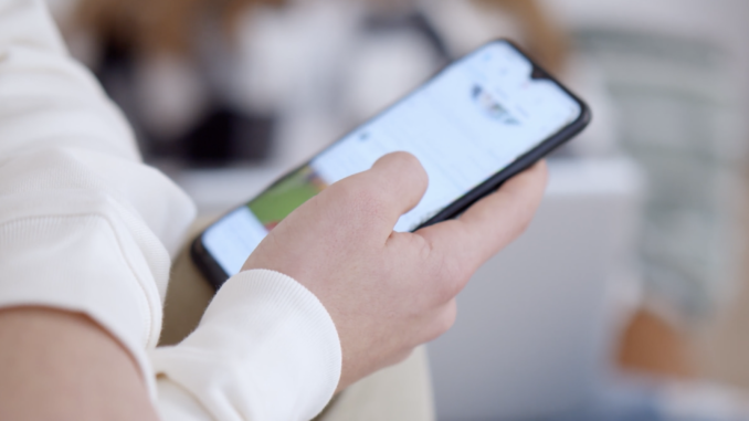 Person holding a smartphone and scrolling a social media feed