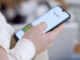 Person holding a smartphone and scrolling a social media feed